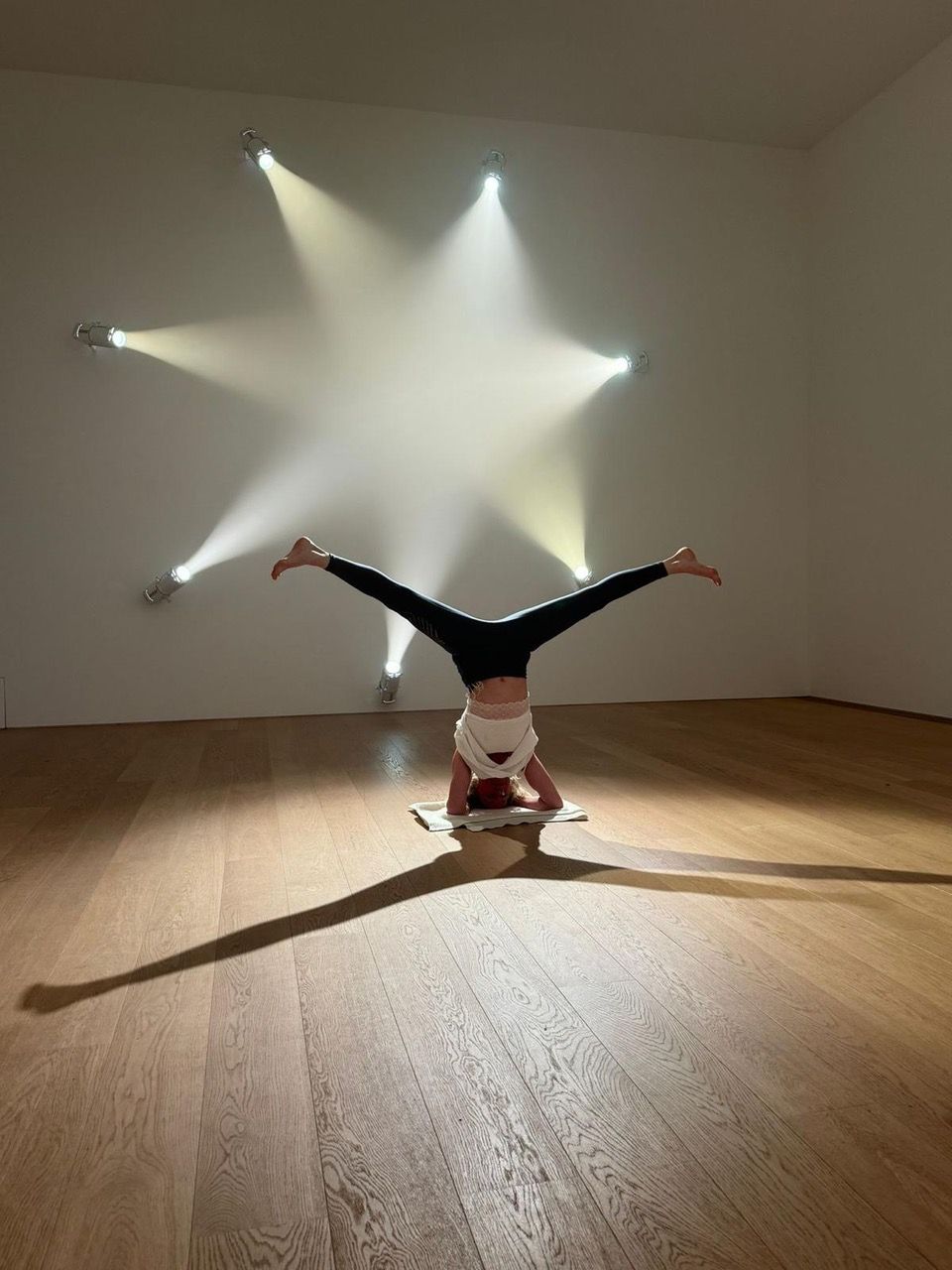 Marelde in een handstand in het licht van zes lampen