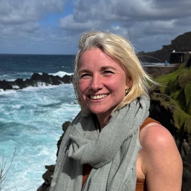 Marelde Net lachend op de rotsen, met de zee achter haar